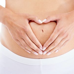 A pregnant woman forming a heart-shape with her hands over her stomach